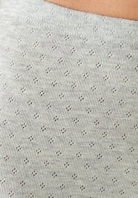Tessuto lavorato a maglia grigio chiaro con un motivo testurizzato di piccoli fori e forme a diamante. Morbido, elastico e traspirante.