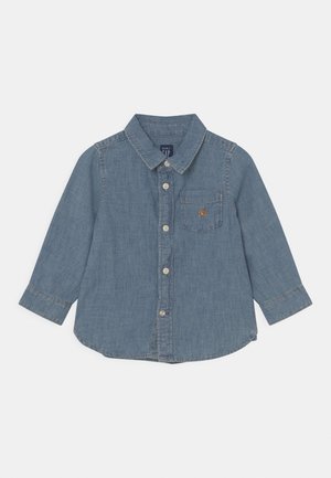 Koszula dżinsowa, jasnoniebieska, z długimi rękawami, zapinana na guziki, z kołnierzykiem, pojedynczą kieszenią na piersi, małe haftowane logo na kieszeni. Gładka tekstura.
