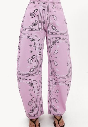 Pantalon large rose avec motifs cachemire et floraux noir et blanc façon bandana, porté avec des sandales ouvertes marron.