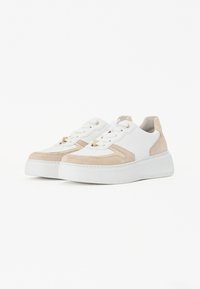 Baskets blanches et beiges avec un mélange de daim et de cuir, présentant une épaisse semelle blanche, un bout rond et des œillets dorés. Les lacets sont blancs.