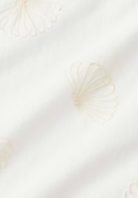 White fabric with raised, cream-colored embroidered seashell patterns arranged across the surface.
