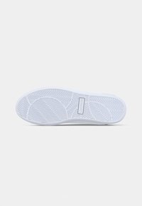 Fehér sneaker talp, amely texturált gumimintával rendelkezik, herringbone és körkörös mintákkal; tartalmaz egy téglalap alakú logó részletet.