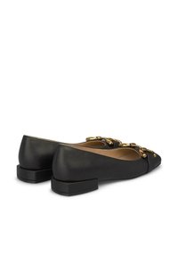 Ballerines en cuir noir avec un petit talon carré, présentant des détails en chaîne dorée sur le devant et un design à bout pointu.