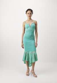 O rochie verde mentă cu un corset din dantelă, decolteu în V, siluetă ajustată și un tiv din dantelă evazat cu o tăietură asimetrică.