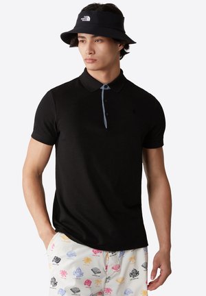 Polo negro de manga corta, con tapeta de dos botones y cuello en contraste azul. Presenta el logo de The North Face en el pecho.