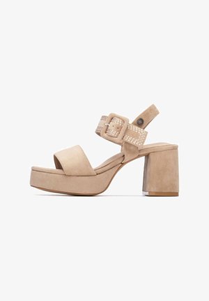 Sandalias de tacón de ante beige con un grueso tacón de bloque, correa ajustable con hebilla y detalles tejidos, y punta redonda abierta.