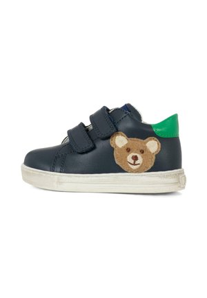 Baskets en cuir marine avec deux bandes Velcro noires. Elles présentent une applique de nounours brun sur le côté et un accent vert au talon.