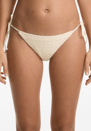 Bas de bikini beige clair avec un motif texturé, doté de liens sur les côtés et d'une coupe triangulaire, fabriqué en tissu doux pour un ajustement confortable.