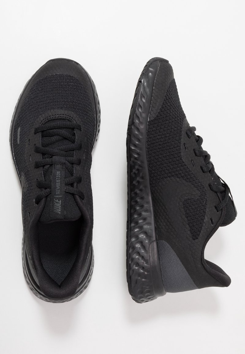 Zapatillas deportivas negras con una parte superior de malla texturizada, punta redondeada y suela de goma gruesa y flexible. Con cordones y un logo en la lengüeta.