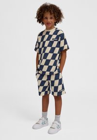 Blå och krämfärgad rutigt kortärmad skjorta och shorts-set, tillverkat av mjukt tyg, med en logotyptryck på bröstet och sidan av shortsen.