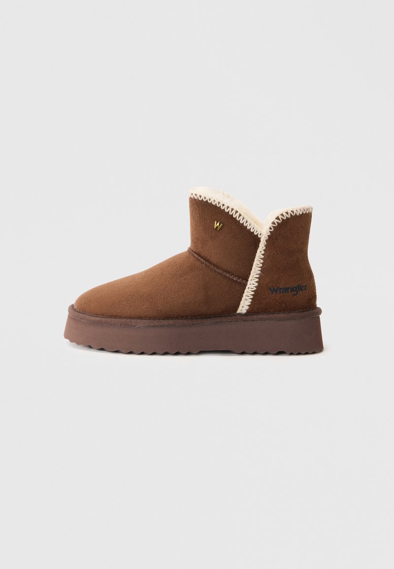 Bottines en suède marron avec une doublure en polaire crème, des coutures en zigzag et une semelle en caoutchouc. Présente une branding 'W' et un logo 'Wrangler' sur le côté.