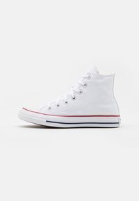Weiße Canvas-Hochschnitt-Sneaker mit Gummisohle, metallischen Ösen, kontrastierenden roten und blauen Seitenstreifen sowie einem runden Zehenbereich.