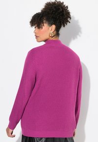 Maglione a maniche lunghe in magenta vibrante, con una texture a coste e un collo alto. La parte posteriore ha una vestibilità rilassata con orlo dritto.