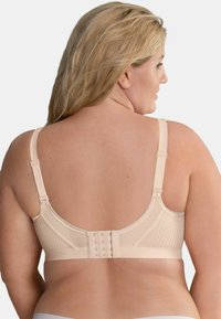 Bra color beige chiaro con un design in rete testurizzata, spalline regolabili e chiusura a gancio sul retro per una vestibilità sicura.