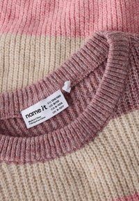 Kootud kampsun, millel on pehmed horisontaalsed triibud roosakasroosa, kreemja ja tuhmi roosa toonides. Lõpetatud soonikkoega kaelusega ja hooldusetikett on nähtav.