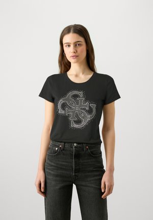 Camiseta de algodón negra con un diseño decorativo de pedrería, con cuello redondo y mangas cortas, combinada con jeans oscuros.