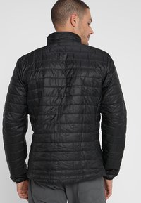 Svart isolerad jacka med kviltad design, hög krage och långa ärmar. Har en slät yta och subtila sömmar.