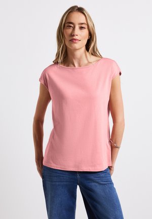 Rosa T-Shirt mit kurzen Ärmeln aus weicher Baumwollmischung, locker geschnitten mit rundem Ausschnitt. Getragen mit blauen Jeans, die einen lässigen Stil zeigen.