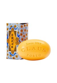 Gelbe ovale Seife mit der Prägung "CLAU" und "PORTO". Die Verpackung zeigt ein blaues und oranges florales Muster mit einem gelben Etikett, das "BANHO CITRON VERBENA" anzeigt.
