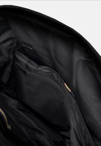 Interno di uno zaino nero con un ampio scomparto, tasca con zip e dettagli a loop multicolori. Texture del tessuto liscia con cuciture rinforzate.