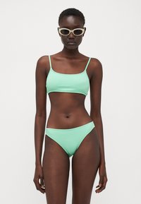 Set di bikini verde menta caratterizzato da un tessuto texturizzato, top corto con scollatura quadrata e spalline sottili, e un paio di slip a vita bassa abbinati.