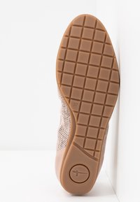 Semelle d'une chaussure rose avec un motif en grille, taille 37 marquée, et un logo circulaire près du talon, photographiée sur fond blanc.