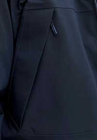 Juodas minkštas švarkas su užtrauktuku, lygia tekstūra ir stilingu dizainu, pasižyminčiu švariomis linijomis ir minimaliais akcentais.