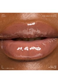 Glossy nude lip gloss applied on full lips with smooth, dark brown skin and natural texture, highlighting shine and hydration.