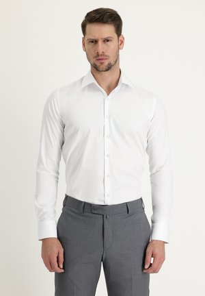 Witte button-up shirt met lange mouwen en een spitse kraag, gecombineerd met grijze broek. Stof lijkt glad met een gestructureerde pasvorm.