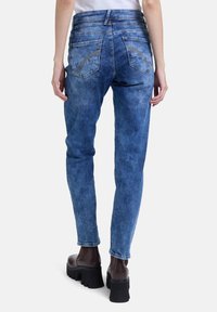 Blauwe denim spijkerbroek met een slim fit, voorzien van twee achterzakken, een vervaagde textuur en een hoge tailleband, gecombineerd met dikke bruine laarzen met hak.