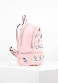 Růžový batoh z umělé kůže s dvojitými zipy, zdobený mnohobarevnými drahokamy a dekorativními kovovými akcenty; kompaktní a kulatý design.