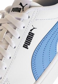 Zapatilla blanca con acentos en azul claro, cuero texturizado, destacado logo negro de Puma y cordones planos blancos. Presenta detalles cosidos.