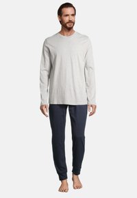 Graues Langarmshirt aus weichem Stoff, kombiniert mit navyblauen, schmal geschnittenen Hosen mit elastischen Bündchen und lockerer Passform.
