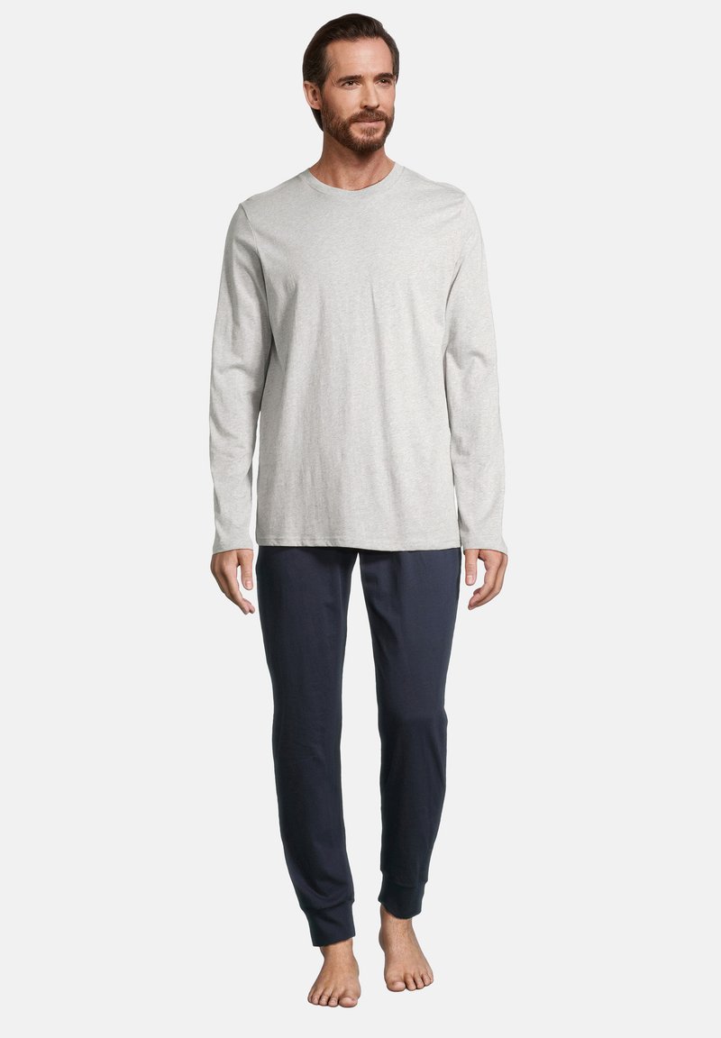 Camicia grigia a maniche lunghe realizzata in tessuto morbido, abbinata a pantaloni tapered blu navy, dotati di polsini elastici e una vestibilità comoda.