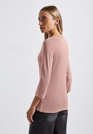 Camicia a maniche lunghe in morbido rosa, realizzata in un misto di cotone, con scollatura rotonda e taglio dritto con cuciture visibili sui lati.