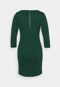 Grön texturerad klänning med trekvartsärmar, figursydd siluett och dragkedja i ryggen. Slätt tyg med ett subtilt mönster.