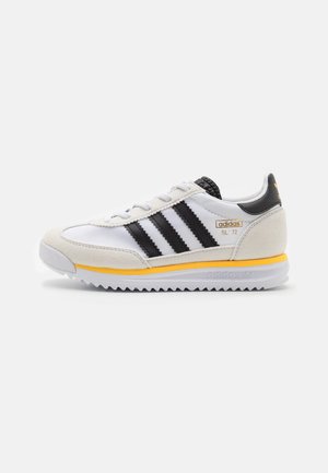 Weißer Adidas SL '72 Sneaker mit schwarzen Streifen, Wildleder-Akzenten, gelbem Mittelsohlenrand und gezackter weißer Außensohle.