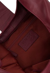 Diep rode leren handtas met een gestructureerde binnenkant, voorzien van een ritsvak en een label met de tekst "VENEZIA Echt Leren."