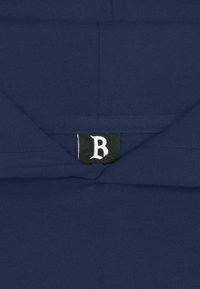 Sweat à capuche bleu foncé avec une étiquette noire au niveau du col, sur laquelle est brodée une lettre "B" blanche en style gothique.
