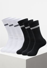 Viererpack Socken: zwei weiße mit schwarzen Streifen, zwei schwarze mit weißen Streifen. Gerippte Textur, mittellange Länge bis zur Wade, Mischgewebe aus Baumwolle.