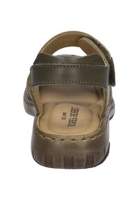 Hnědé kožené sandály s nastavitelným zeleným popruhem, texturovaným svrškem a polstrovanou podrážkou. Obsahují viditelné švy a branded vložku.