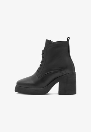 Melni ādas potīšu zābaki ar augstu taisnstūrveida papēdi, noapaļotu purngalu, saistīšanas priekšpusi un cilpu aizmugurē. Gluda tekstūra, minimālistisks dizains.