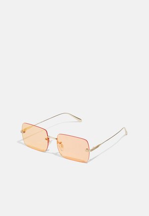 Auksiniai metaliniai akinių rėmeliai su stačiakampiais oranžiniais lęšiais. Išskirtinai plonos šakos ir subtilūs tekstūriniai akcentai šalia vyrių.