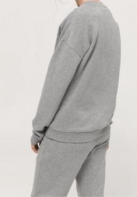 Grå bomullströja med långa ärmar och rundad halsringning, med ribbade ärmslut och nederkant, kombinerad med matchande grå joggers.