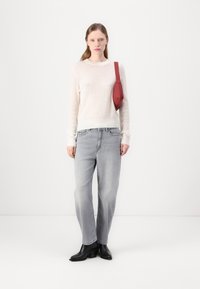 Hvit stripete strikket genser, lys grå rette jeans og svarte hælede støvletter. Rød crossover-veske fremhever antrekket.
