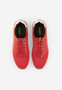 Sneakers rossi con tomaia in rete, punta rotonda e accenti bianchi a contrasto sul colletto. Presentano lacci piatti e una soletta imbottita.