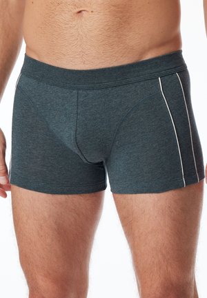 Boxer in grigio scuro realizzati in tessuto morbido, con accenti bianchi sui lati e un design aderente. Hanno un elastico in vita a media altezza.