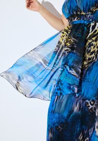 Blaues und schwarzes gemustertes Kleid aus fließendem, transparentem Stoff. Mit Akzenten im Tierdruck und strukturierten Schichten. Elegantes und leichtes Design.