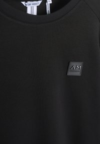 Felpa nera a girocollo con un patch del logo testurizzato. Realizzata in tessuto liscio con una leggera lucentezza. Etichetta con informazioni sul brand visibile.