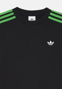 T-shirt in cotone nero con accenti a tre strisce verdi sulle spalle e un logo ricamato bianco sul petto.